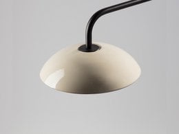 A wall lamp with a dome-shaped shade made of ceramic material in various colors, including black, white, beige, green, red, yellow, grey, and blue. The lamp has a minimalist, modern design with a black metal arm.