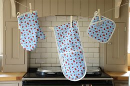 Colorful polka dot oven mitts with a ladybird design, made of cotton material, suitable for kitchen use.