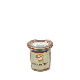 A jar of extra boletus coulis, a pasta sauce made from boletus mushrooms. The jar has a label with the product name and is surrounded by pieces of dried boletus mushrooms on a wooden surface.