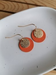 Vibrant orange-gold statement earrings with a glittery, textured center.