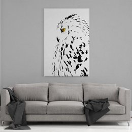 A large, framed canvas print featuring a close-up portrait of a snowy owl with a white and black feather pattern. The owl's piercing yellow eyes are the focal point of the image.