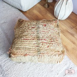 A round, plush Moroccan-style pouf in shades of pink and beige with a geometric pattern, suitable for use as an ottoman or extra seating.
