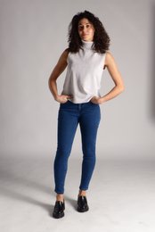 Women's skinny jeans in dark blue denim with a white sleeveless top.