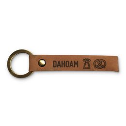 Leather keyring with metal ring, featuring the text "Dahoam" and icons of a dirndl and pretzel, in a traditional Bavarian style.