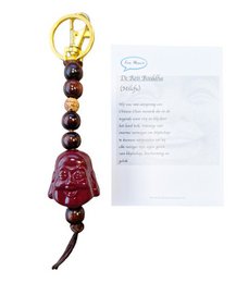 Burgundy red Buddha bell keychain, wooden beads, gold-tone metal, spiritual charm, travel accessory.