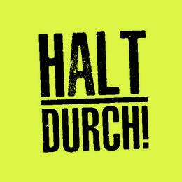 Sticky notepad with bold "HALT DURCH!" text in black on a bright yellow background. The notepad is placed on a wooden surface next to a computer keyboard and mouse.