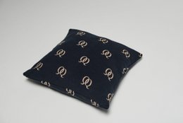 Cushion cover with a repeating pattern of gold-colored horseshoe shapes on a dark navy background. The cushion cover has a square shape and appears to be made of a soft, textured fabric.
