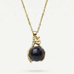  A gold-toned necklace with a blue glass pendant, featuring a sand-like texture and a gold star accent. The necklace is presented in a light blue drawstring pouch.