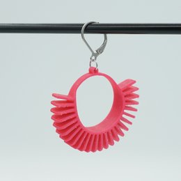 Statement earrings in vibrant colors including gold, magenta, melon yellow, and purple. The earrings feature a circular shape with radiating fan-like ridges, creating a bold and eye-catching design.