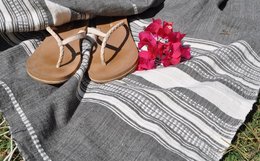Charcoal and natural colored handmade throw blanket with floral sandals.