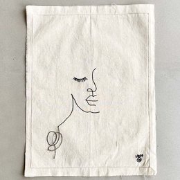 Minimalist line art poster featuring a simple face design. The poster has a neutral, off-white background with a black line drawing of a face with closed eyes.