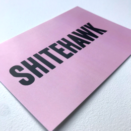 A pink postcard with the text "SHITEHAWK" printed in bold black letters.