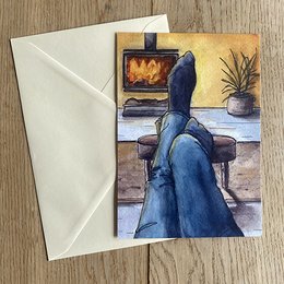 A cozy fireplace scene with a person sitting in a chair, wearing a long blue dress and looking out the window. The image has a warm, rustic feel with a potted plant and a fireplace visible.