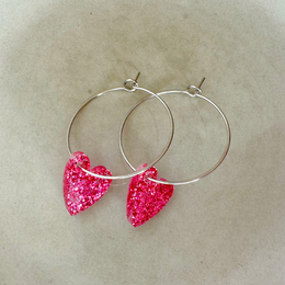 Magenta heart-shaped hoop earrings with a festive, glittery charm design.