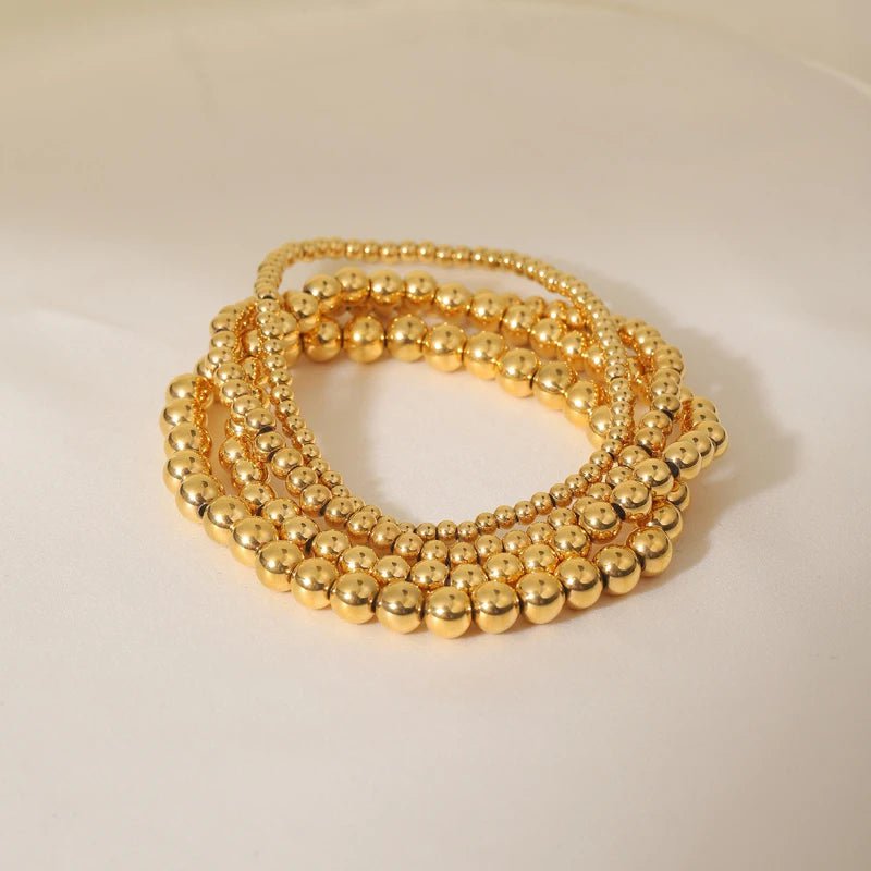 Aquilea - Pile de bracelets en perles d'or