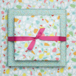 Turquoise and white wrapping paper with a colorful terrazzo pattern and a green ribbon.