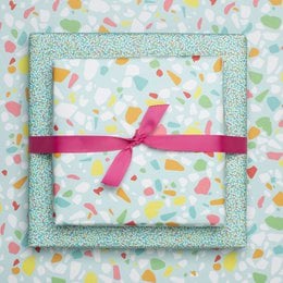 Turquoise and white wrapping paper with a colorful terrazzo pattern and a green ribbon.