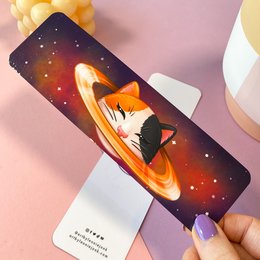 Caturn Laminated Bookmark - A whimsical space-themed bookmark featuring a sleeping fox curled up on a crescent moon against a starry night sky background.