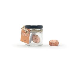 Sunstone crystal in a glass jar with an orange label. The sunstone is a warm, reddish-orange color and has a natural, irregular shape.