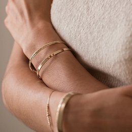 Gold-toned circular bangle bracelet with a simple, minimalist design.