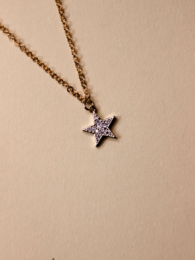Delicate gold-tone necklace with a sparkling star pendant adorned with purple crystals.