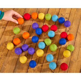  Colorful felt balls in a variety of vibrant hues, including red, orange, yellow, green, blue, and purple. The balls appear to be arranged in a playful, scattered pattern on a wooden surface.