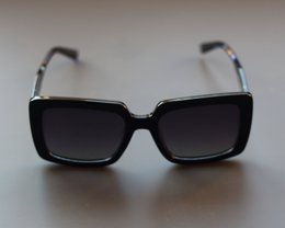 Black square oversized sunglasses with blue tortoiseshell arms, dark tinted lenses, modern style.