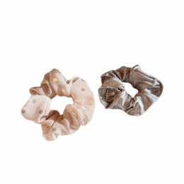 A pink and gold scrunchie made of a soft, textured fabric with a shimmery appearance.