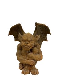 A large, brown gargoyle statue with bat-like wings and a fierce, snarling expression. The gargoyle appears to be made of cast iron or a similar heavy, durable material, suitable for outdoor garden decor.