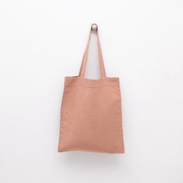  A beige linen tote bag with a simple, minimalist design. The bag has a rectangular shape and a single strap for carrying.
