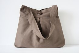 Brown shoulder bag made of durable fabric with a large strap and decorative button closure.