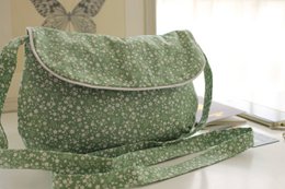  Green floral shoulder bag with snap closure and adjustable strap.