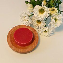 Pomegranate-scented, palm oil-free soap bar with a round, red shape.