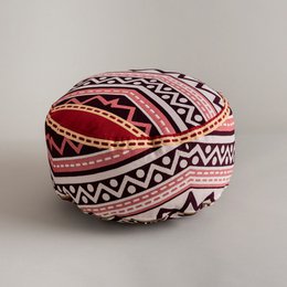 Decorative round meditation pillow with a vibrant, patterned design featuring geometric shapes and lines in shades of red, black, and white.