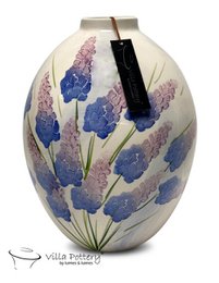 Tall, cylindrical vase with a floral design featuring blue and purple flowers against a light background.