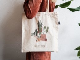 Fairtrade tote bag with a nature-inspired graphic design and the text "Time to grow". Made of durable cotton material.