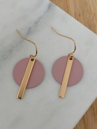 Statement earrings in old rose gold color with a round disc and a vertical bar accent.