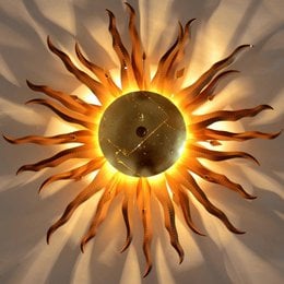Hand-forged sun-shaped wall light with rust and gold colors.