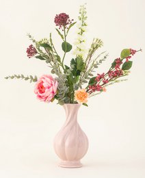  Vibrant bouquet of pink roses, greenery, and other colorful flowers in a white ceramic vase.