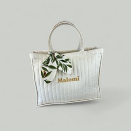 Vanilla cream quilted mother's bag with Malomi branding, featuring a structured rectangular shape, quilted texture, and a decorative leaf accent.