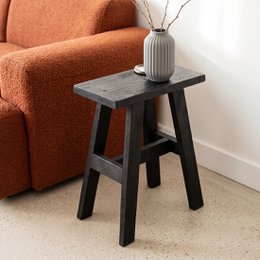 A black, rectangular bench with a simple, minimalist design. The bench has a sturdy, A-frame style base and a flat, rectangular top surface.