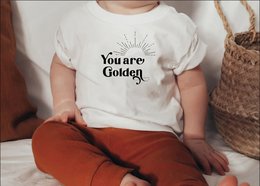 Kids t-shirt with "You are Golden" text and sun graphic. White t-shirt with black text and graphic. Available in sizes 0-3 months to 12-13 years.