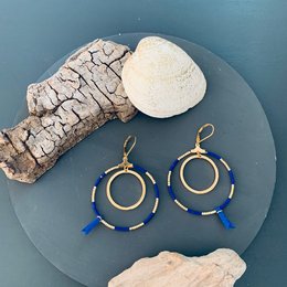 Statement earrings in bold gold-tone hoops with blue beaded accents. Elegant and eye-catching design.