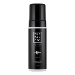 Tan self-tanning mousse in instant/medium shade, packaged in a black bottle with The Tan Co. branding. Suitable for all skin tones, provides a natural-looking, streak-free tan.
