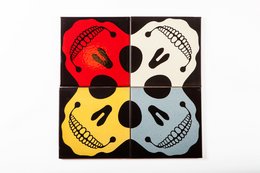 Colorful abstract wall art featuring four skull-like designs in red, white, yellow, and blue on a black background.