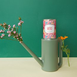 Colorful floral tin canister labeled "Merci" with a festive, celebratory design.