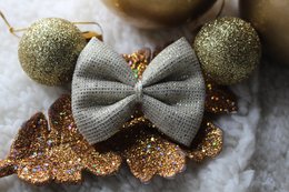 Gold glitter hair clip with gray bow, perfect for the holiday season. Suitable for kids' hair accessories.