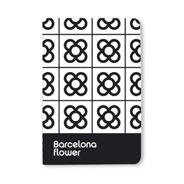 A compact black and white notebook with a repeating geometric pattern and the text "Barcelona flower" printed on the cover.
