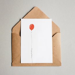 A simple, minimalist birthday card featuring a single red balloon on a white background, enclosed in a brown envelope.