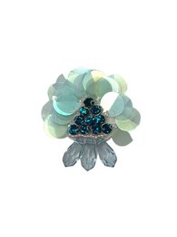 A colorful brooch featuring a floral design with shades of green, blue, and black. The brooch has a unique and eye-catching appearance, making it a stylish accessory for any outfit.